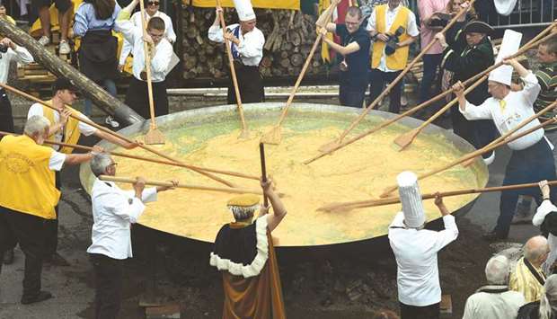 Members of the World Giant Omelette Brotherhood prepare the 6,500-egg omelette using a 4m diameter frying pan in Malmedy.