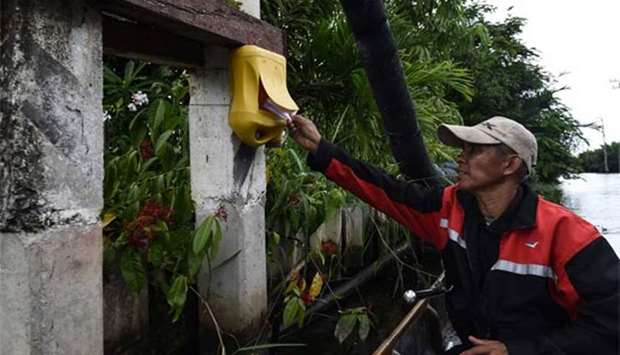 Postman Nopadol Choihirun putting mail in a postbox along the canal in the Bang Khun Thian district on the outskirts of Bangkok.