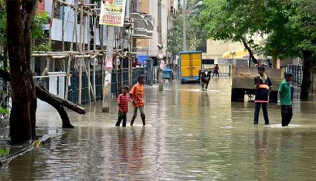 Residents wade through rain water in a low-lying area in Bengaluru on Tuesday.