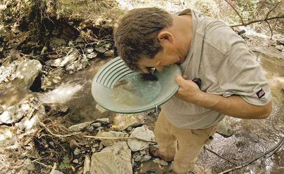 Robert Guardiola of Riverbank uses a magnifying glass to teach for gold in his pan after collecting gravel deposits under the waterfall on his claim, south of Eagle Creek This yearu2019s historic rains and runoff are scouring Californiau2019s rivers and streams, leaving gold fever in the air.