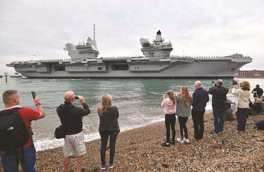 People line the shore to watch as tug boats manoeuvre the 65,000-tonne aircraft carrier HMS Queen Elizabeth into Portsmouth Harbour in Portsmouth, southern England, yesterday morning.