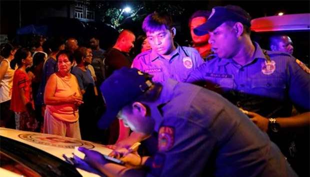 Police officers write a report about a man who was killed in drug-related violence in Manila.