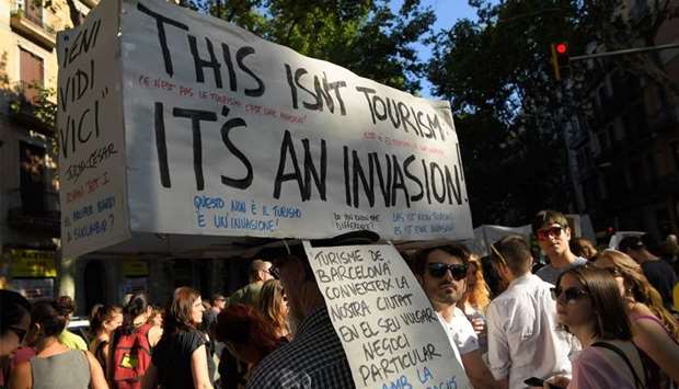 Protesters carry a banner that reads, ,This isn't tourism, it's an invasion, during a demonstration in Barcelona
