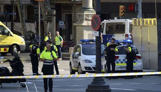 Medical staff members and policemen stand in a cordoned off area after a van ploughed into the crowd in Barcelona