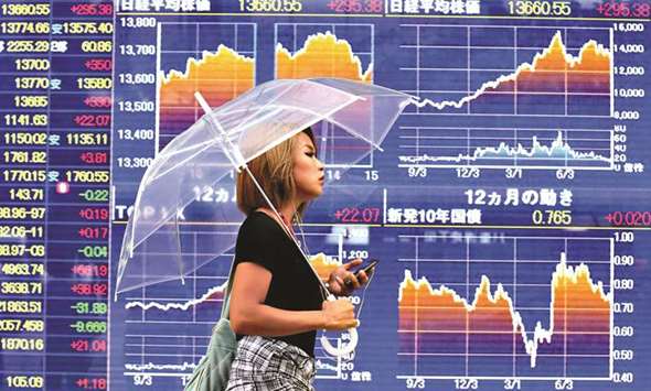 A woman walks past an electronic monitor displaying graphs of Japanu2019s various stock indices outside a securities firm in Tokyo (file). Japanu2019s longest string of quarterly  economic expansion in more than a decade and continued growth in corporate earnings have emboldened bullish equity strategists.