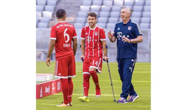 This file photo shows Bayern Munich coach Carlo Ancelotti (R) and Bayern Munichu2019s midfielder Juan Bernat hobbling on crutches.