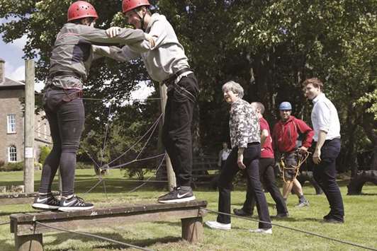 Prime Minister Theresa May talks with participants as they attempt to traverse an activity at the Woodlands Outdoor Education Centre in Glasbury, eastern Wales. May unveiled a new course that will be developed by National Citizen Service to help raise awareness of mental health amongst young people, and improve their knowledge of how to get help.