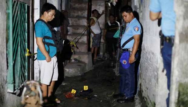 Policemen stand guard at the crime scene after three men were killed during a police anti-drug operations in Caloocan city, Metro Manila.