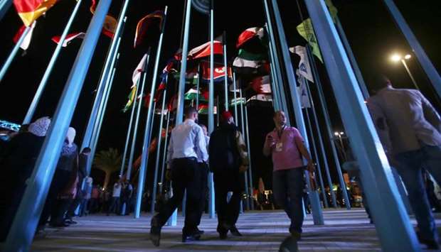 Participants and visitors walk past flags of various countries during the opening of the Damascus International Fair late yesterday.
