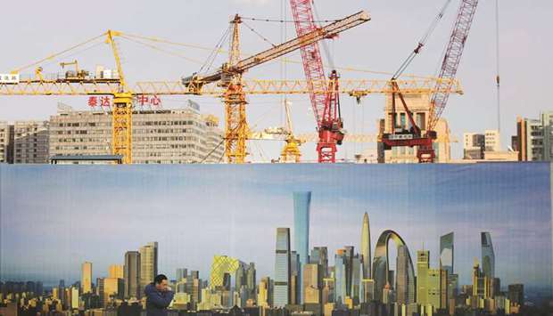 A man walks past the hoarding of a construction site in Beijing. In Chinau2019s biggest markets, Beijingu2019s new home prices fell 0.1% in July, after declining 0.4% in June.
