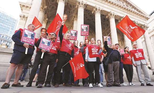 Protesters hold up masks of Bank of England Governor Mark Carney and wave flags and placards outside the bank as it staff began a three-day strike over pay, in the City of London.