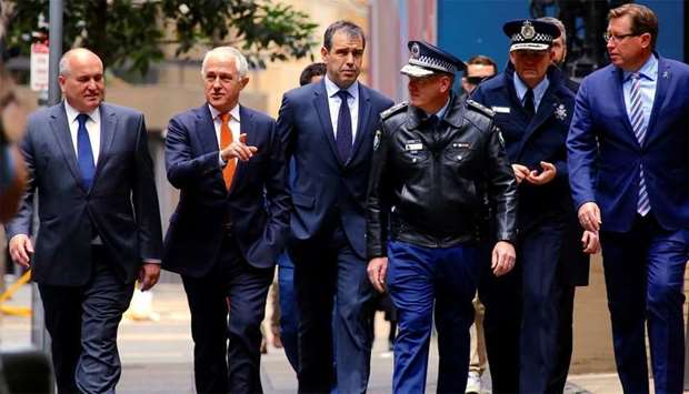 Australian Prime Minister Malcolm Turnbull walks with officials along a street before holding a media conference announcing Australia's national security plan to protect public places in central Sydney