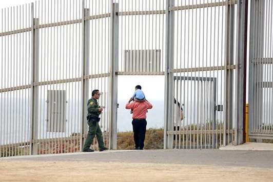 A US Border Patrol agent escorts a family through the secondary fence back to Border Field State Park, San Diego, after visiting people in Friendship Park, Tijuana, along the U.S.-Mexico border in Tijuana.