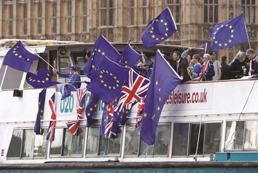 Anti-Brexit, pro-European Union Remain supporters wave flags as they travel up and down the River Thames outside the Houses of Parliament in London on Saturday evening.