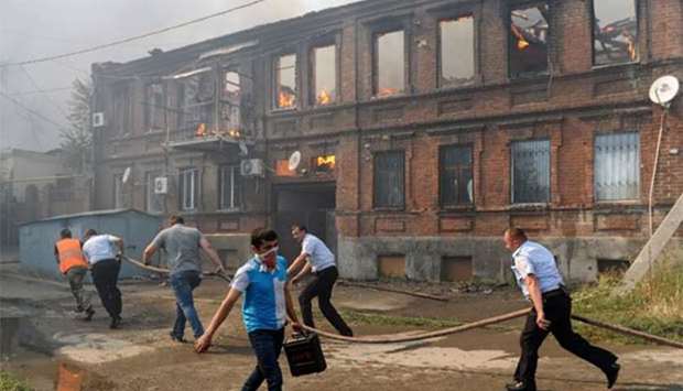 Police officers and municipal workers attempt to extinguish a fire that engulfed a residential area in the southern Russian city of Rostov-on-Don on Monday.