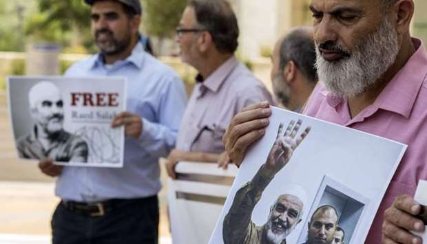 Arab-Israeli supporters of Sheikh Raed Salah (portrait), leader of the radical northern branch of the Islamic Movement in Israel, gather in protest against the arrest and detention of the Sheikh, outside the Israeli Rishon Lezion Justice court, near Tel Aviv on August 17, 2017