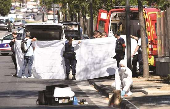 A white sheet is erected around the body of a victim as it is moved into a waiting ambulance while a French forensic police officer searches the site in the southern Mediterranean city of Marseille.
