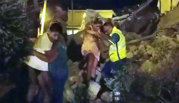 A woman is helped out of debris and rubble after an earthquake hit the island of Ischia
