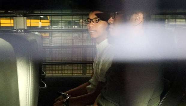 Democracy leader Joshua Wong sits in a prison van as he arrives at the High Court in Hong Kong