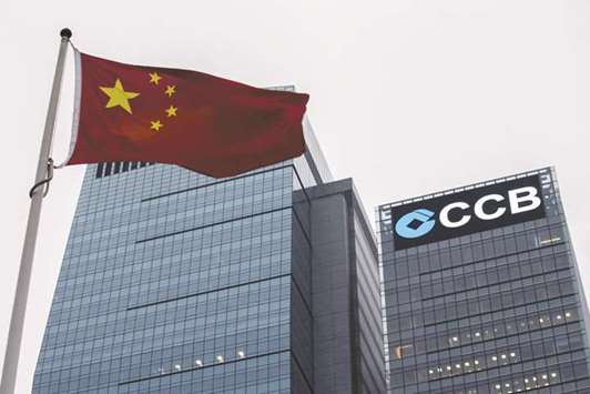 A Chinese national flag flies in front of the China Construction Bank tower at Hong Kongu2019s central business district. Chinau2019s second-biggest bank by assets has been conducting roadshows to raise at least 100bn yuan ($15bn) from onshore and offshore investors, people close to the matter said yesterday.