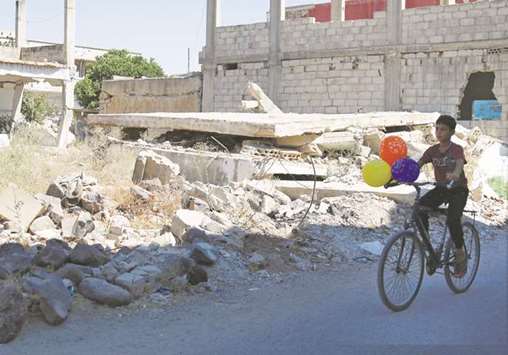 A boy rides a bike along a damaged street in a rebel-held area in the town of Dael, Syria.