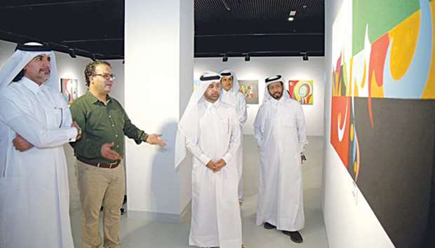 The artist explains his artwork to Dr al-Sulaiti and other dignitaries.