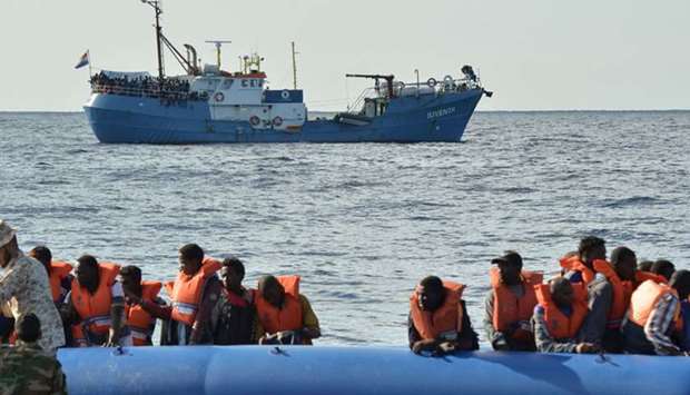 A picture taken on November 4, 2016 migrants and refugees sitting on a rubber boat as the Libyan coastguards patrol help them during a rescue operation with the ,Iuventa,, (rear C) a rescue ship run by young Dutch NGo ,Jugend Rettet, (Youth Saves), sailing off the Libyan coast the Mediterranean sea.