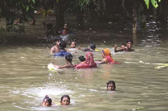 Villagers wade and swim through flood waters in Alal village in Malda in West Bengal yesterday.