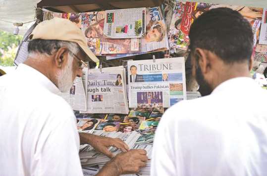 Pakistani residents buy newspapers with front page headlines about US President Donald Trump at a stall in Islamabad yesterday.