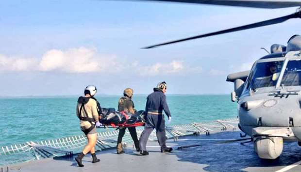 Royal Malaysian Navy personnel carry a body onto a US Navy helicopter
