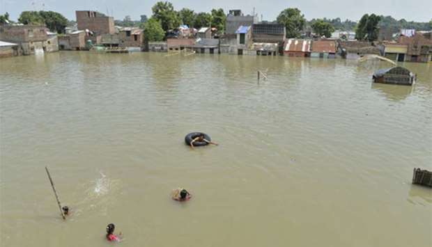 Residents swim and wade through flood waters in Malda in the Indian state of West Bengal