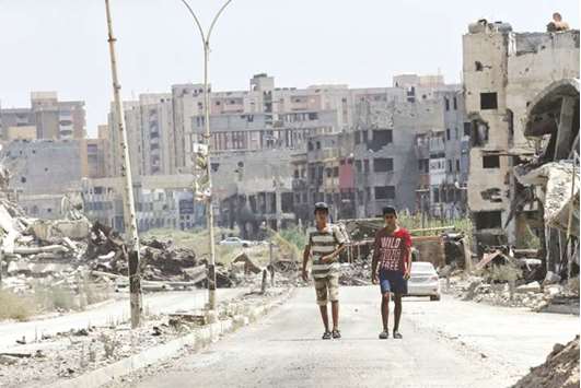Men walk near destroyed buildings in Sabri, a central Benghazi district.