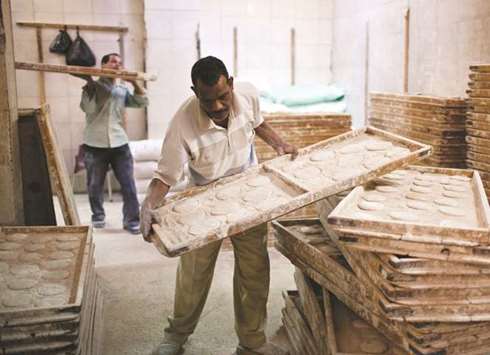 Workers arrange trays of dough for baking bread in a bakery in Cairo. Egyptu2019s Public Prosecution Office is looking into the case after the quarantine office stopped a 63,000-metric-tonne Romanian wheat cargo shipment at the port of Safaga for containing poppy seeds, the Agriculture Ministry said.