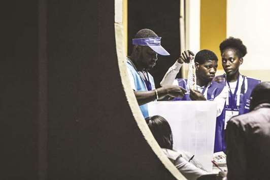 Polling station officials show ballot papers during the counting of the ballots at the end of the general election vote in Luanda.