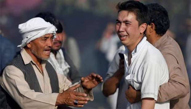 Afghan men comfort a man whose relatives were killed in a suicide attack on a mosque in Kabul on Friday.