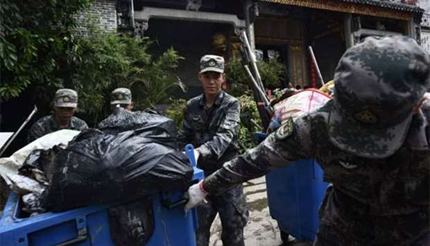 Chinese People's Liberation Army soldiers help clear debris from outside a temple in Macau on Friday, two days after Typhoon Hato hit the territory.