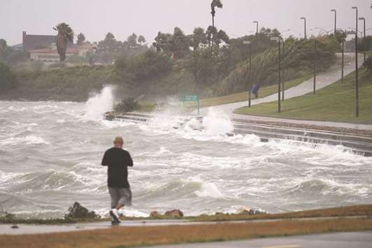 Sal Valerio walks near bay waters as they churn from approaching Hurricane Harvey in Corpus Christi, Texas. Hurricane Harvey has intensified into a hurricane and is aiming for the Texas coast with the potential for up to 3 feet of rain and 125 mph winds.