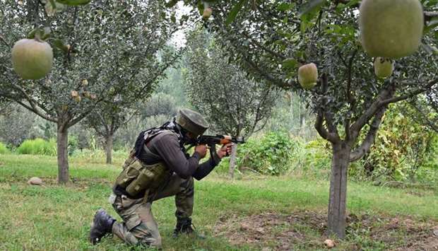 An Indian army soldier stands guard in an apple orchard while a gunfight takes place between militants and government forces in Pulwama, south of Srinagar.  AFP