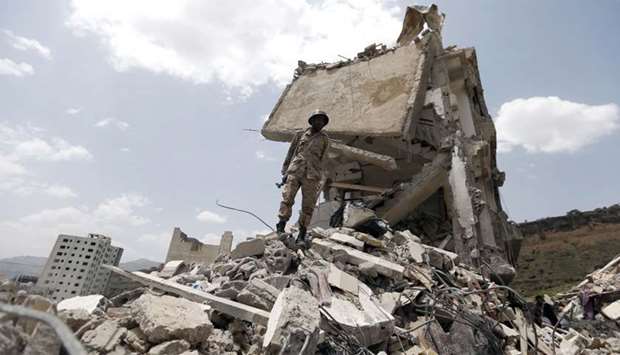 Yemeni soldier stands on the debris of a house, hit in an air strike on a residential district in Sa
