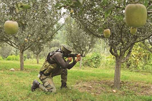 A soldier stands guard in an apple orchard while a gunfight takes place between militants and government forces in Pulwama, south of Srinagar, yesterday.