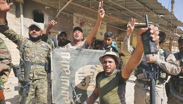 Iraqi troops flash the victory gesture as they hold upside down a banner bearing the logo of the Islamic State group, during the advance in the town of Tal Afar.