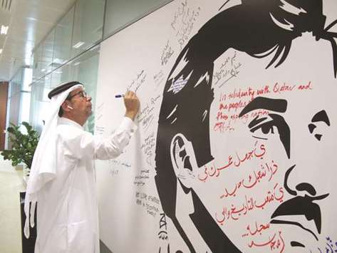 A QPM official signs u2018Tamim Al Majdu2019 mural.