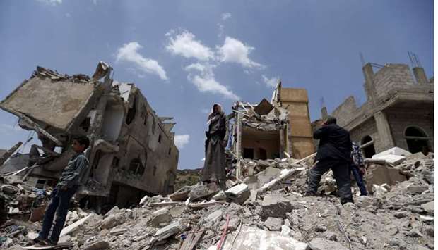 Yemeni men stand on the debris of a house, hit in an air strike on a residential district, in the capital Sanaa yesterday.
