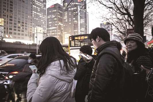 Commuters using smartphones stand in line at a bus station in Beijing. Chinau2019s so-called old-economy companies are enjoying a renaissance in the debt market, bouncing back from a beating on Beijingu2019s quest to modernise growth.