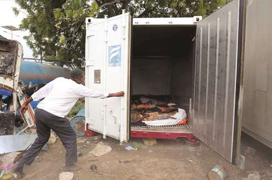 A man opens the refrigerator of a truck used as a morgue to show the bodies of people killed in an attack by Somali forces and supported by US troops.