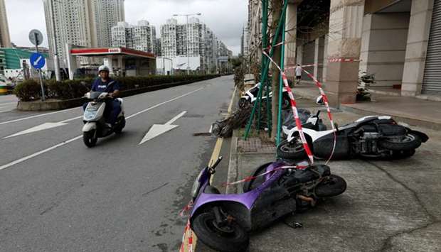 A man looks at motorcycles tipped over by strong wind from tropical storm Pakhar in Macau.