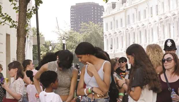 The burned-out shell of the Grenfell tower block overlooks people gathering on the first day of the Notting Hill Carnival in west London.