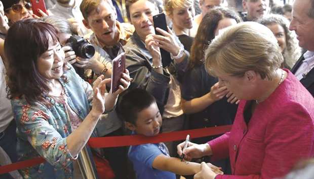 Merkel signs on a childu2019s arm at the Chancellery in Berlin during the governmentu2019s u2018Open Door Dayu2019.