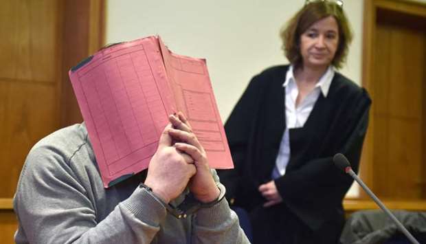German former male nurse Niels H hiding his face behind a folder as he waits next to his lawyer Ulrike Baumann (R) for the opening of another session of his trial on February 26, 2015 at court in Oldenburg, northwestern Germany.