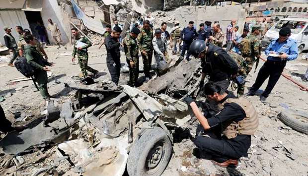 Iraqi security forces inspect the site of a car bomb attack in Jamila market in Sadr City district of Baghdad